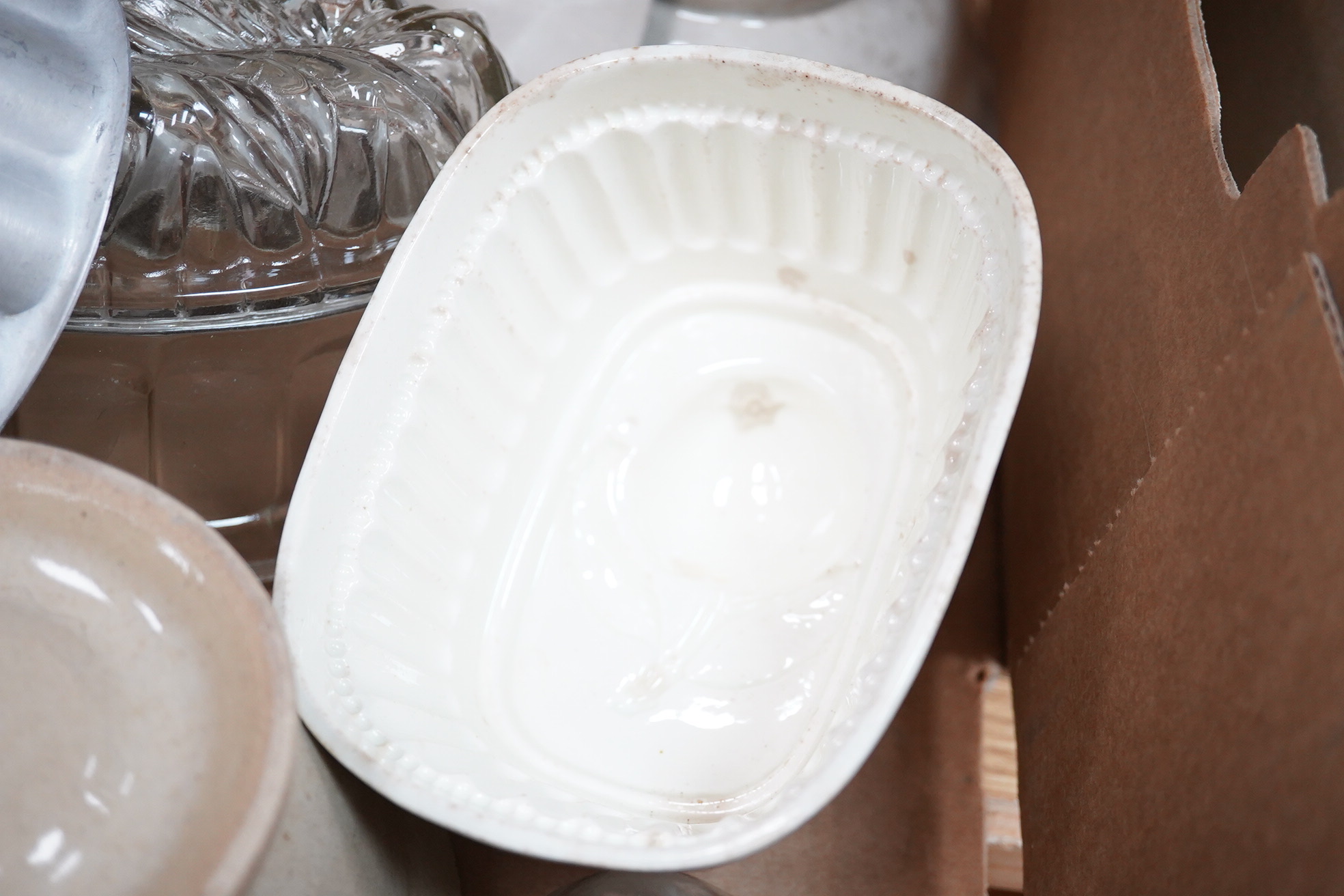 A collection of mostly Victorian ceramic and later glass and metal jelly moulds